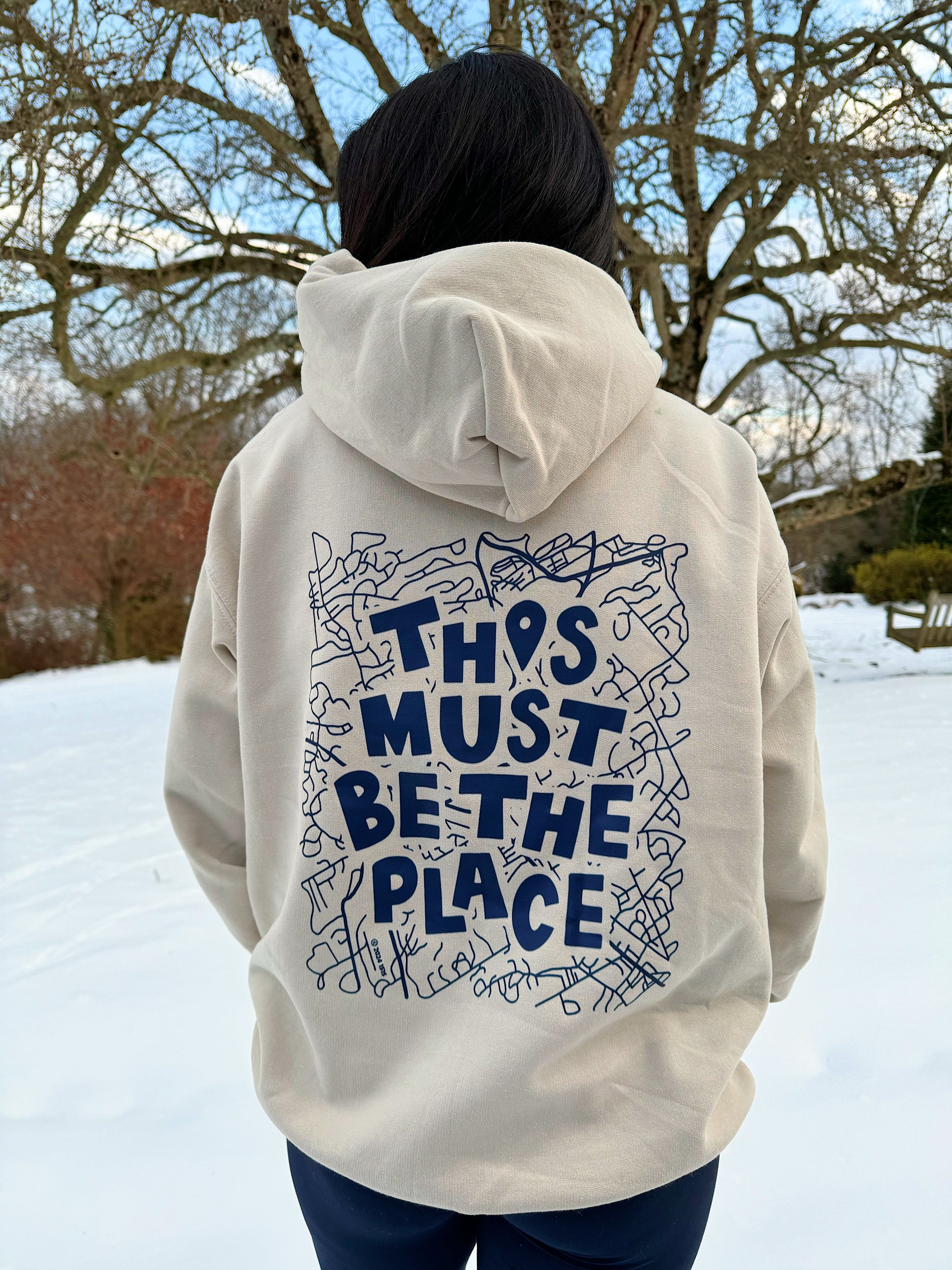 Tan Unisex Hoodie with Navy Writing. Ally is wearing a size large.